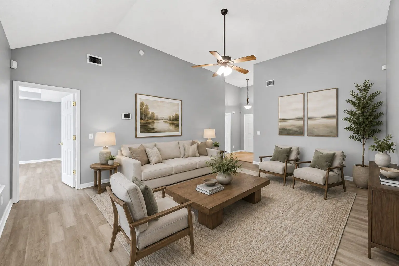 Same living room after virtual staging with sofa, chairs, rug, and coffee table